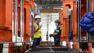 Two men in hard hats stand in a factory, discussing operations at MCON.