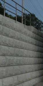 A concrete wall is positioned next to a building, illustrating the MCON design approach in urban settings.