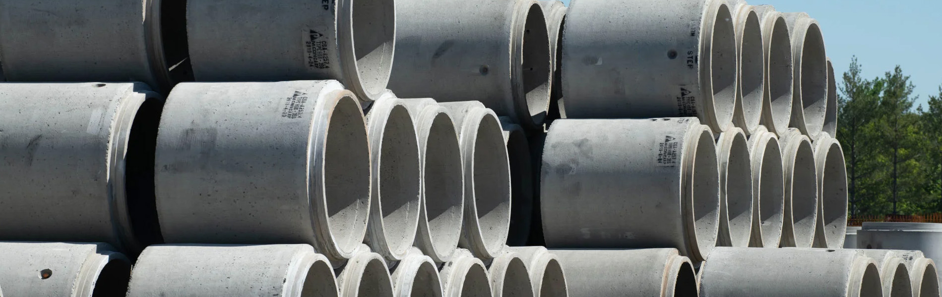 A stack of concrete pipes from MCON Precast Products, showcasing their durable construction and industrial design.