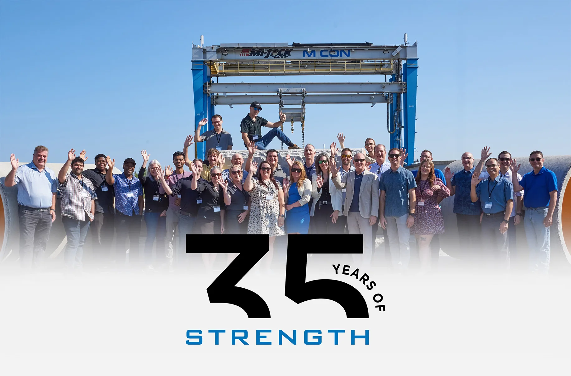 A group of people celebrating in front of a sign that reads "35 Years of Strength" for MCON's 35 Year Anniversary.